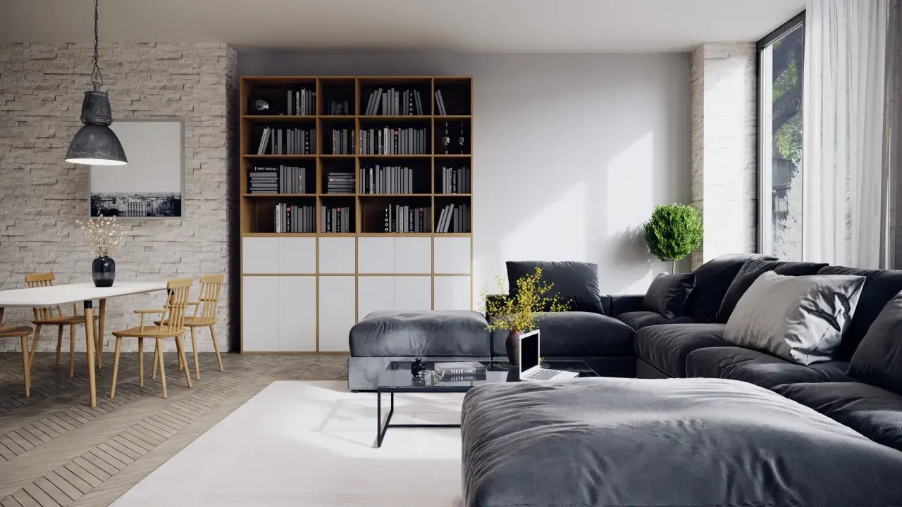 Un salon moderne avec un grand canapé d'angle gris foncé, une bibliothèque remplie de livres, une table basse et une table à manger en bois clair.