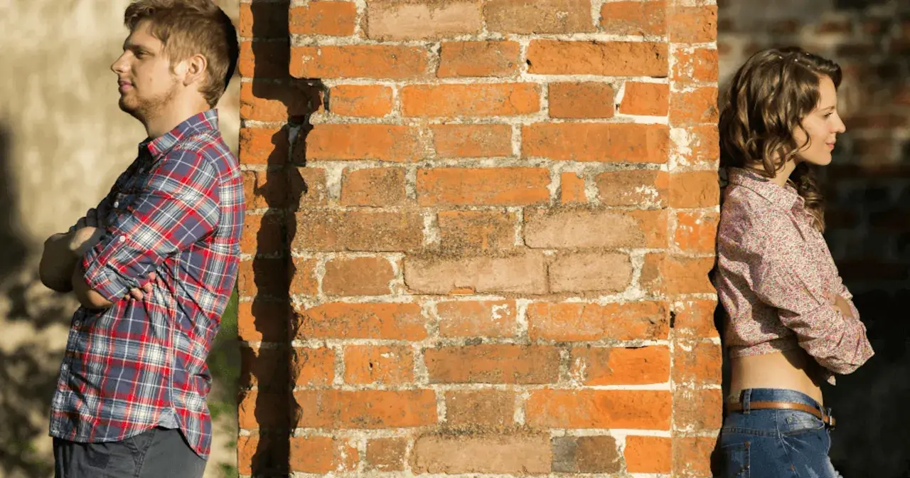 Un homme et une femme se tiennent de part et d'autre d'un mur de briques. Peut-on fixer quelque chose sur un mur mitoyen ?