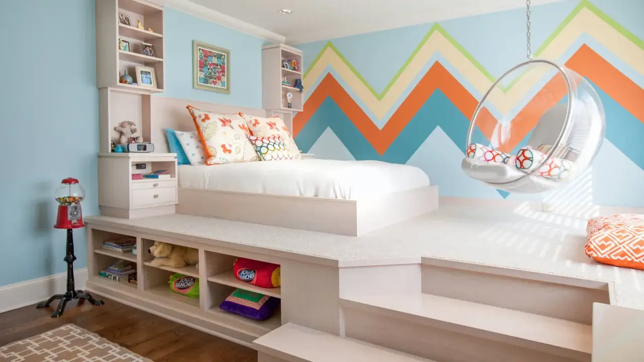 Chambre fille petit espace avec lit sur estrade, rangements intégrés, fauteuil bulle et mur géométrique coloré.