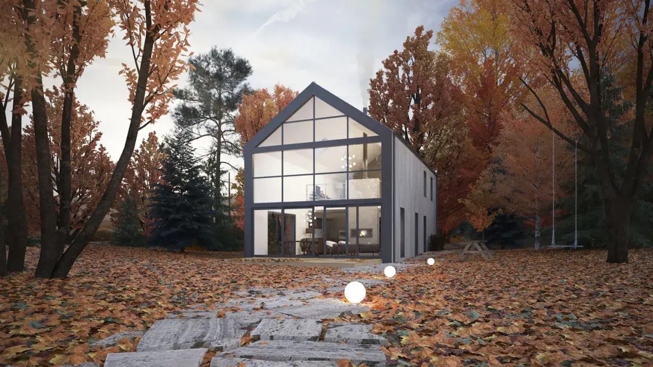 Maison moderne avec un grand pignon vitré, entourée d'arbres aux couleurs d'automne. Un chemin de dalles mène à la porte d'entrée.