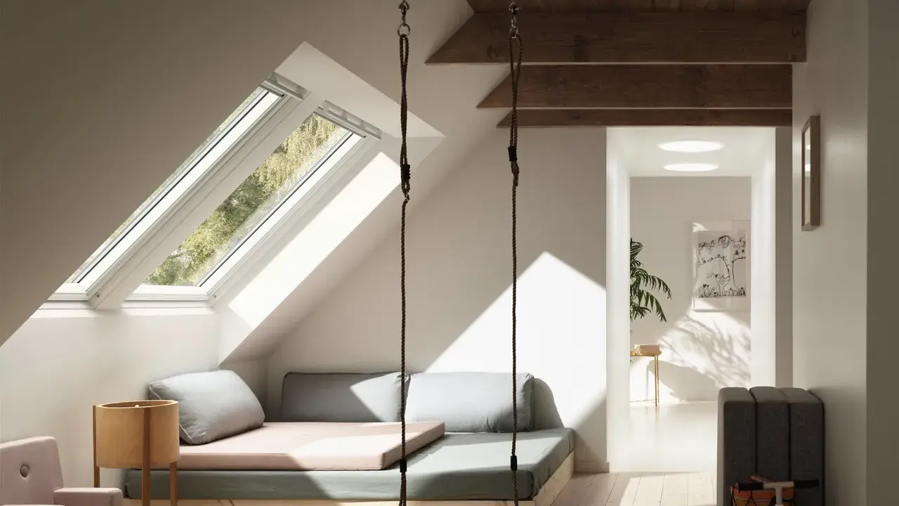 Aménagement comble 1m50 : un espace cosy avec balançoire, lit bas et vue sur la nature par les fenêtres de toit.