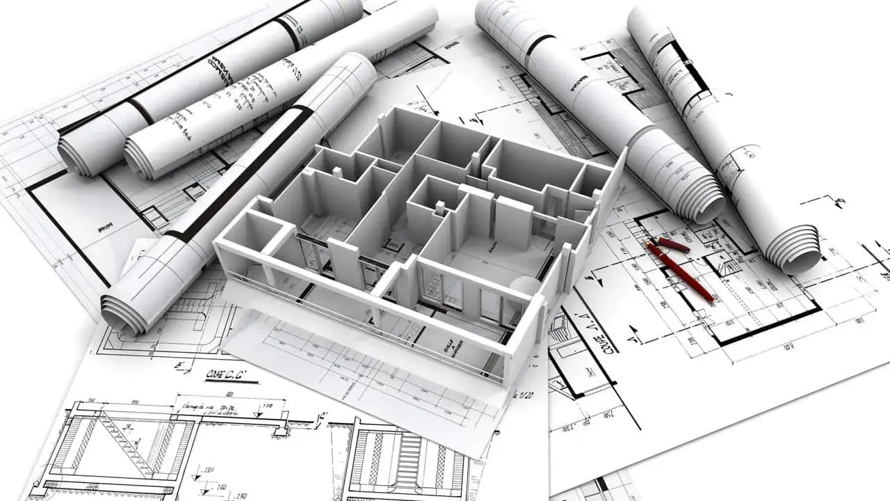Maquette 3D d'une maison familiale sur des plans d'architecte, avec des rouleaux de plans et des stylos rouges.