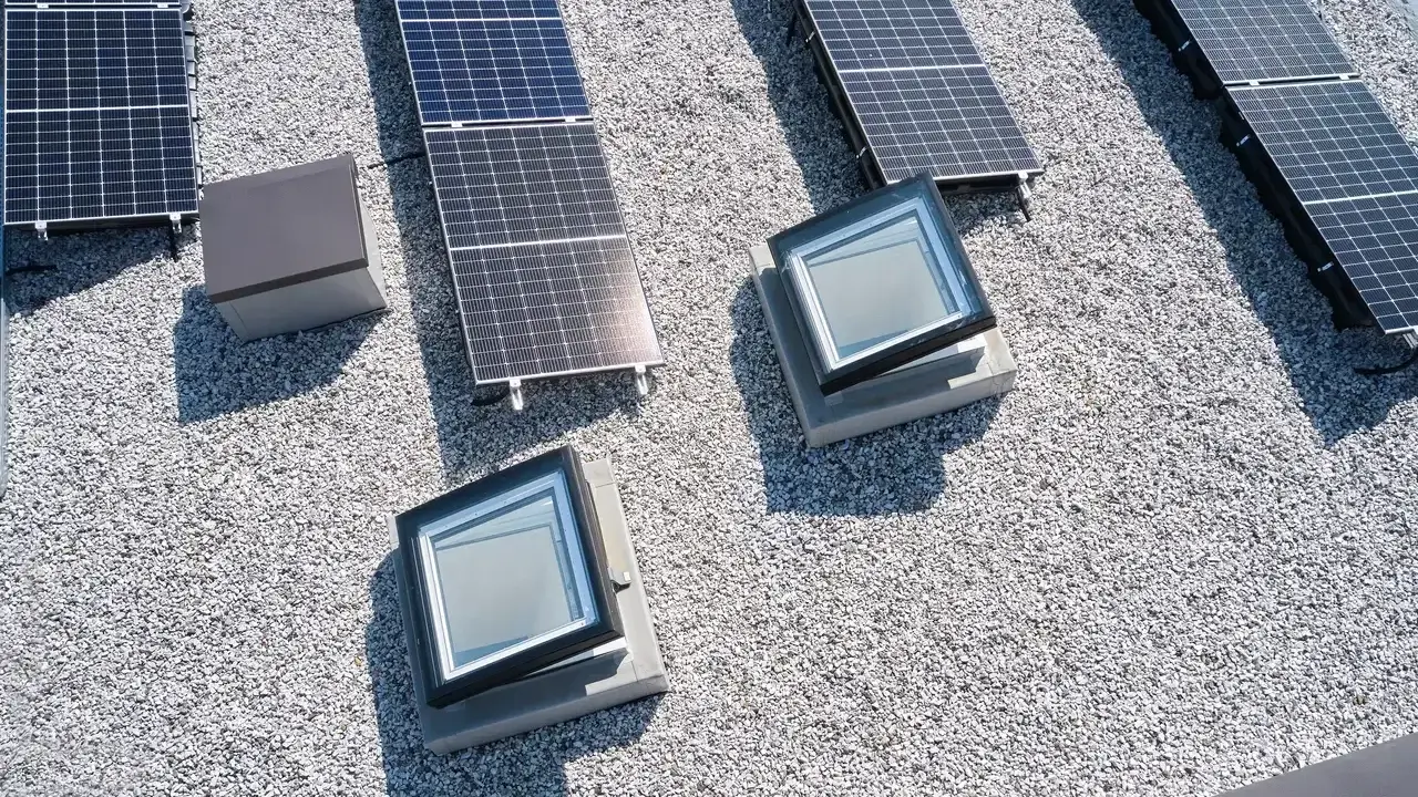 Vue aérienne d'une maison toit plat avec panneaux solaires et deux fenêtres de toit.