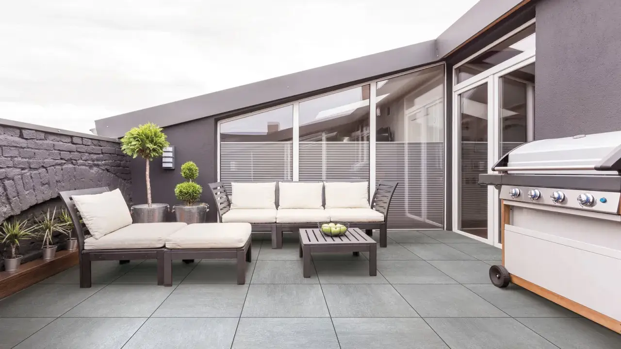 Terrasse moderne avec mobilier de jardin et barbecue. Le carrelage extérieur antidérapant est facile à nettoyer.