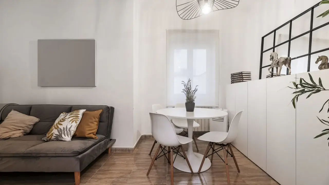 Idée pour aménager salon salle à manger 20m2 : canapé gris, table ronde blanche avec chaises, et rangements muraux.