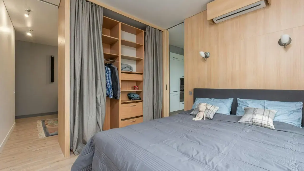Chambre moderne avec lit douillet, dressing ouvert et rideaux gris. Le prix pour peindre une chambre de 12m2 dépend des finitions.