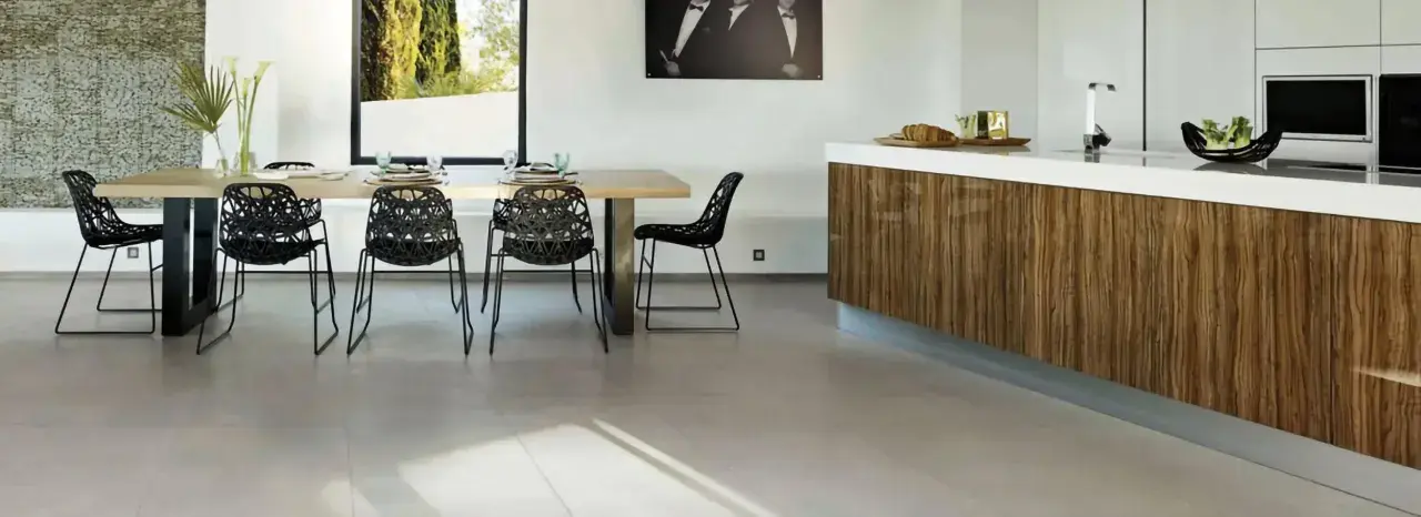 Un salon moderne avec un carrelage pièce de vie tendance, une table en bois, des chaises noires design et un îlot de cuisine en bois veiné.