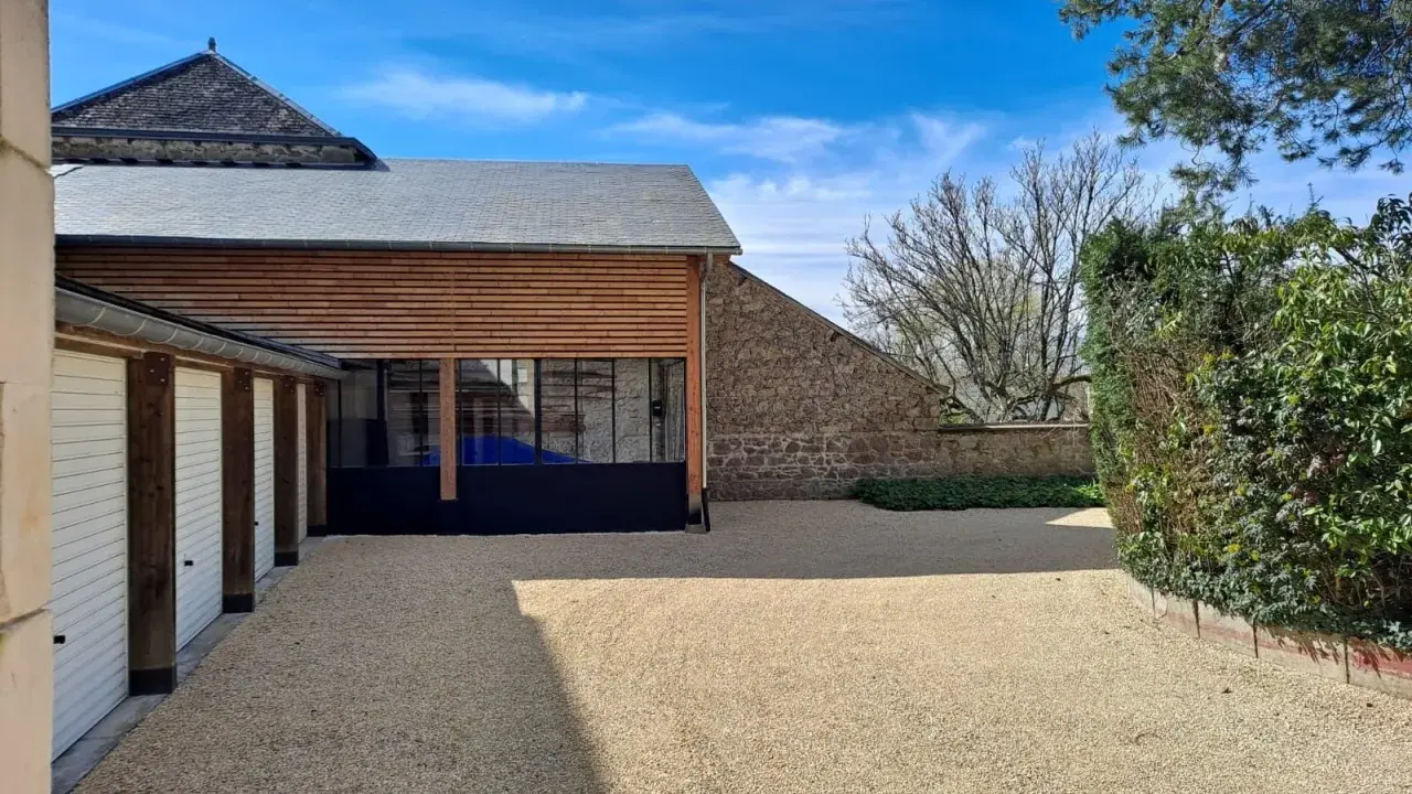 Belle maison tradi pierre Saint Junien avec garage, jardin et ciel bleu.