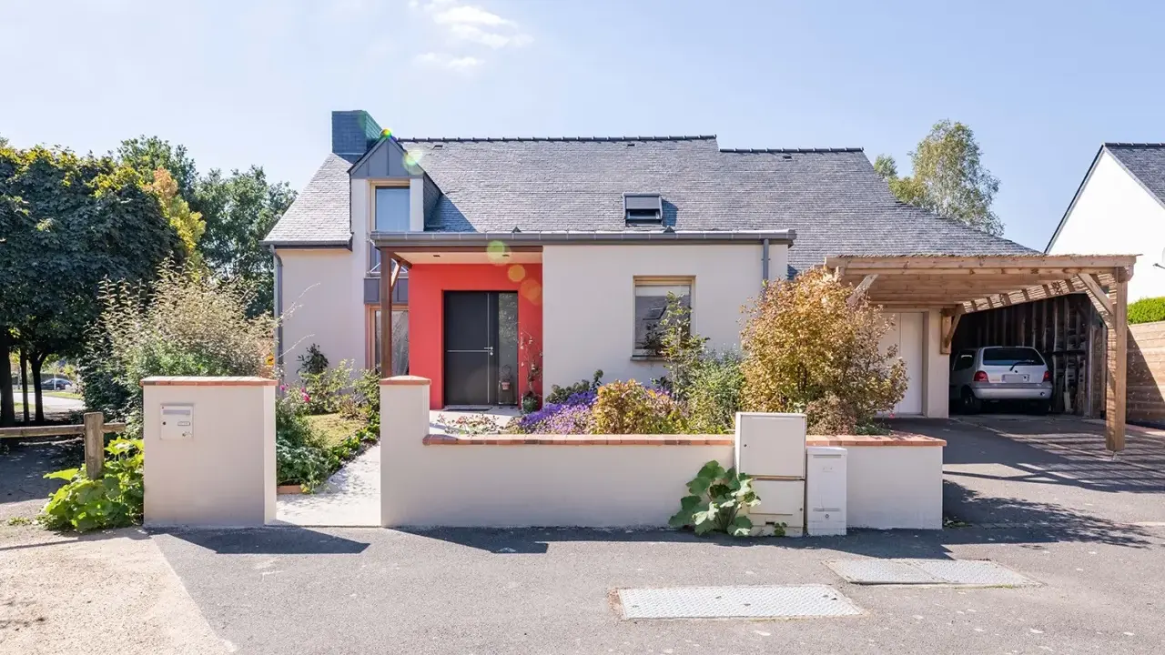 Maison moderne avec entrée rouge vif et carport en bois. Idéal pour estimer le prix rénovation maison m2.