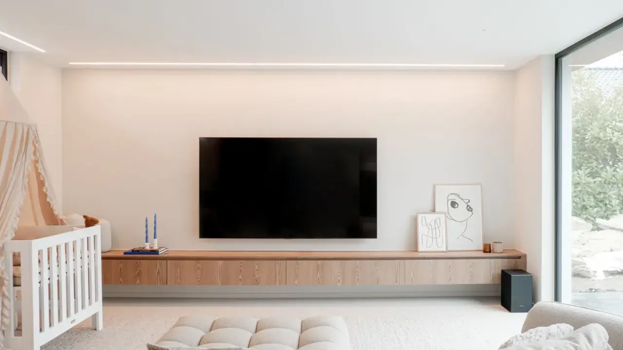Meuble TV en bois clair, suspendu, offrant une belle profondeur. Une télévision est fixée au mur au-dessus.
