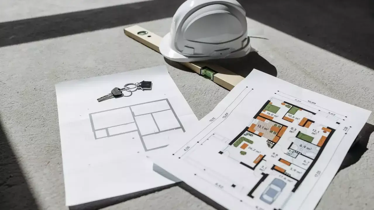 Clés, casque et niveau à bulle sur des plans d'architecte, un aperçu d'un projet de construction. Un plan architecte gratuit pour concrétiser vos rêves.