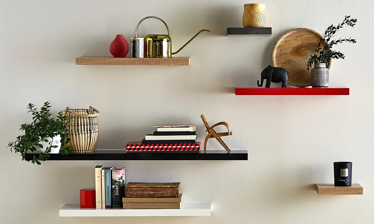 Étagères flottantes décorées : plante, arrosoir doré, livres, éléphant, bougie. La hauteur entre étagère varie pour un design dynamique.