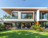 Une maison futuriste aux lignes épurées, avec de grandes baies vitrées, des balcons et une végétation luxuriante.