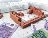Plans de maison, briques et billets en euros symbolisant le prix construction maison 150m2.