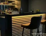 Bar moderne avec éclairage LED intégré dans des tasseaux de bois. Idée déco pour un coin bar chic.