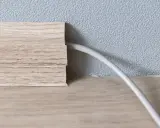 Une plinthe en bois imite le bois et cache un fil électrique. Astuce pour comment cacher des fils électriques.