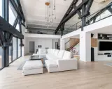 Salon moderne avec poutres apparentes, canapé blanc, escalier en bois. Ce style peut influencer le prix renovation appartement.