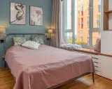 Une chambre d'amis confortable avec un lit douillet, des tableaux de fleurs et une vue sur la ville.