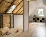 Aménagement de combles : isolation en laine de verre, murs en plaques de plâtre et sol en OSB. Fenêtres de toit et étagères.