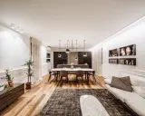 Un grand salon moderne avec un canapé blanc, une table à manger ovale et une cuisine intégrée. La taille du salon est optimisée pour le confort.