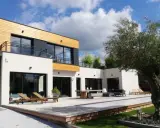 Maison moderne avec un style architectural audacieux, mêlant bois et blanc. Terrasse spacieuse avec mobilier extérieur et piscine.