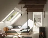 Aménagement comble 1m50 : un espace cosy avec balançoire, lit bas et vue sur la nature par les fenêtres de toit.
