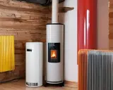 Plusieurs appareils de chauffage, dont des poêles à granulés et des radiateurs, sont alignés sur un mur en pierre. Un système de chauffage naturel pour un intérieur cosy.