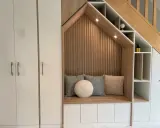 Aménagement cage d'escalier avec banquette confortable, coussins douillets et rangements intégrés.
