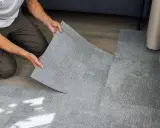 Pose d'une nouvelle moquette pour cacher un manque de carrelage. Les dalles grises s'assemblent parfaitement.