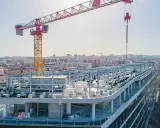 Grue de chantier sur un bâtiment en construction rapide, avec une ville en arrière-plan.