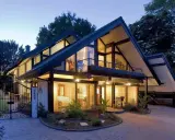 Maison moderne avec grandes fenêtres, balcons et jardin. Le prix d'une maison autonome comme celle-ci peut varier.