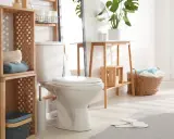 Idées pour comment décorer des toilettes : étagères en bois, paniers tressés, plantes vertes et serviettes douces créent une ambiance chaleureuse.