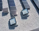 Vue aérienne d'une maison toit plat avec panneaux solaires et deux fenêtres de toit.