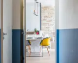 Peinture couloir 2 couleurs : un mur blanc cassé et bleu marine divise l'espace. Une porte s'ouvre sur une salle à manger moderne.