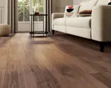 Un salon lumineux avec un nouveau revêtement sol en bois chaleureux, un canapé crème et des coussins décoratifs.