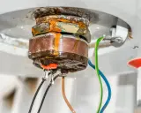 Gouttes d'eau tombant d'une chaudière qui fuit par le bas, signe de corrosion et de problèmes imminents.