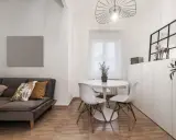Idée pour aménager salon salle à manger 20m2 : canapé gris, table ronde blanche avec chaises, et rangements muraux.