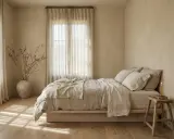 Chambre paisible aux tons sable, avec un lit douillet, des rideaux légers et une bougie. Une ambiance qui invite à se demander quelle est la meilleure couleur pour une chambre.