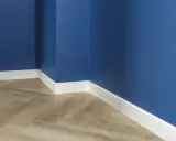 Un coin de pièce aux murs bleu profond, avec un parquet imitation bois clair et un élégant type de plinthe blanc.