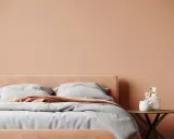 Lit de chambre douillet avec mur et tête de lit couleur pêche. Quelle couleur chambre pour une ambiance chaleureuse et apaisante.