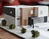 Maquette d'une maison individuelle moderne aux lignes épurées, avec des éléments en carton et des arbres stylisés.