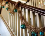 Guirlande dorée et boules de Noël bleues et blanches pour décorer une rampe d'escalier pour Noël.