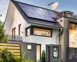 Une maison passive moderne avec des panneaux solaires sur le toit, une clôture en bois et une boîte aux lettres.