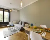 Un salon salle à manger de 20m2 prêt pour le petit-déjeuner, avec un canapé confortable, une table en bois garnie de croissants et de jus d'orange, et une grande fenêtre lumineuse.