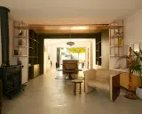 Espace de vie lumineux en enfilade : salon avec poêle, salle à manger et cuisine ouvrant sur le jardin.