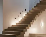 Un élégant miroir reflète la lumière douce d'une montée d'escalier moderne, créant une ambiance chaleureuse et accueillante.