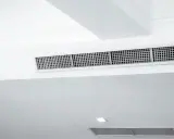 Grille de climatisation par le plafond, discrète et intégrée dans un design moderne pour un confort optimal.