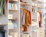 Un dressing bien organisé avec des vêtements suspendus, des étagères remplies de livres, de boîtes et de sacs. Idéal pour organiser son dressing.