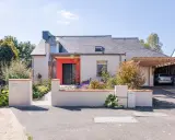 Maison moderne avec entrée rouge vif et carport en bois. Idéal pour estimer le prix rénovation maison m2.