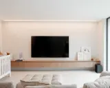 Meuble TV en bois clair, suspendu, offrant une belle profondeur. Une télévision est fixée au mur au-dessus.